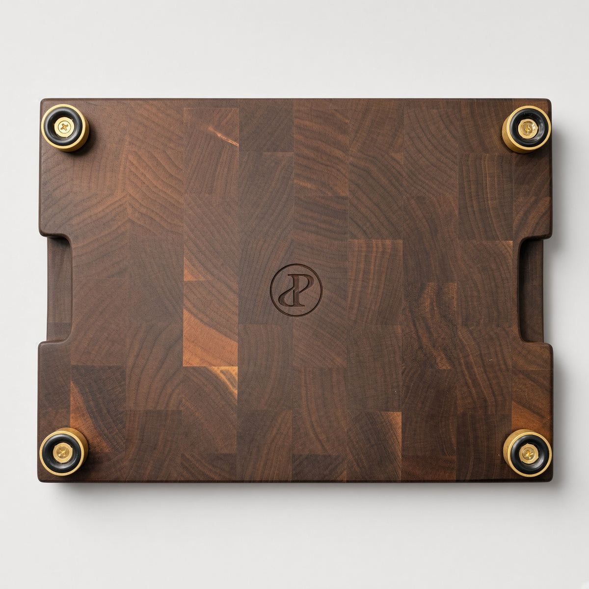 A premium everyday end-grain cutting board with Brass feet.

Materials: Base is walnut wood with a hard maple inlay.

Design: With a carved skeleton chef grilling next to a charcoal grill, with the text 'NOU GAAN ONS BRAAI' below.

Uses:
- Chopping Board
- Cheese or Meat Board
- Charcuterie Board
- Biltong Board

Note: Wood is a natural material, and the received product will have wood color and grain variations compared to this picture.